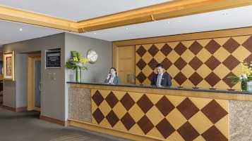 A reception desk with a check-in counter, a clock, and a framed certificate on the wall.