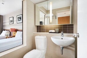 A modern bathroom with a toilet, sink, and a large mirror.