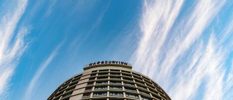 A tall, curved hotel building with a clear sky in the background.