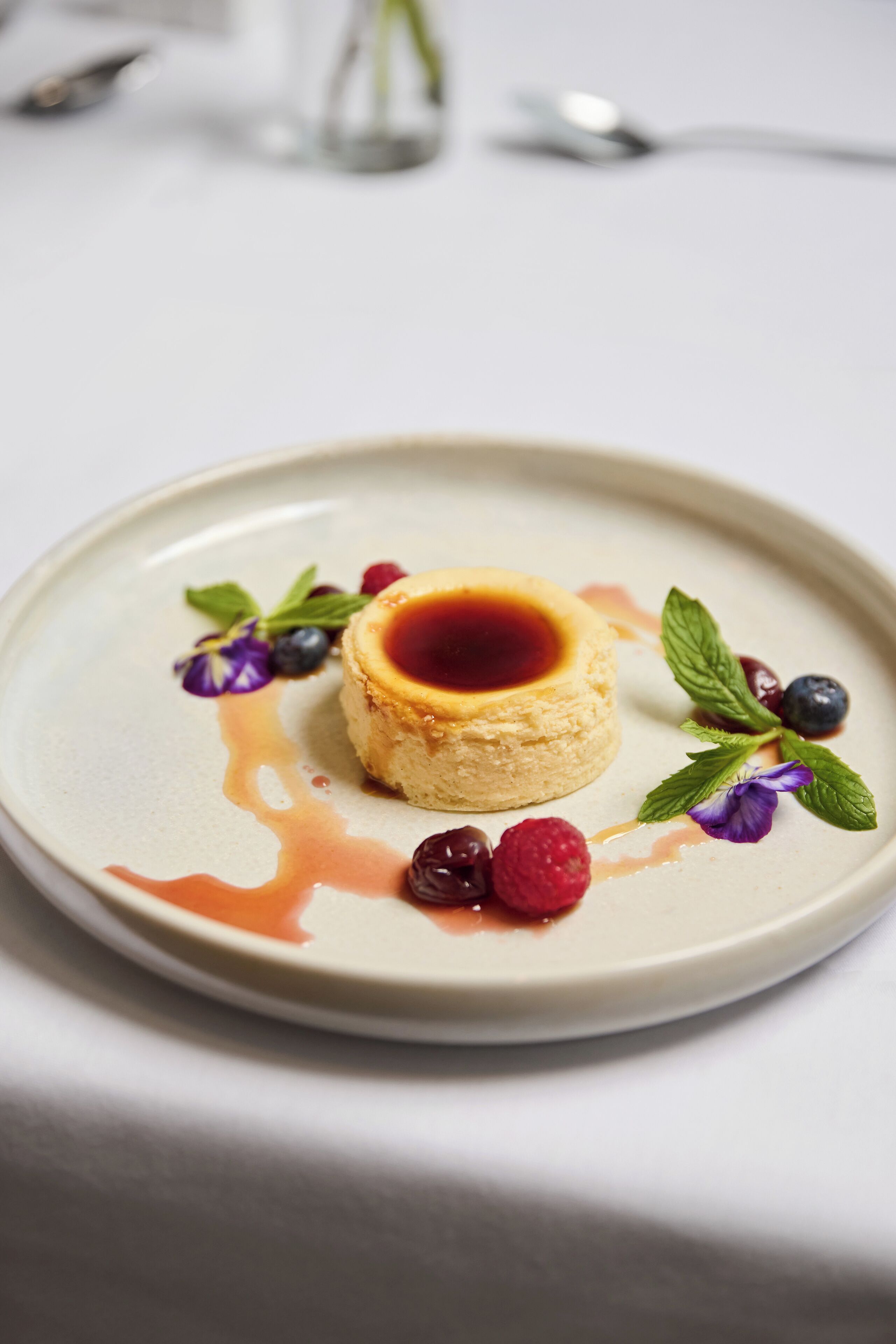 A dessert on a plate with berries and mint leaves.