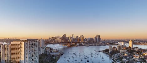 A high-rise hotel with a view of the harbor and the city skyline, including a prominent bridge.