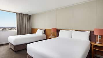 A hotel room with two beds, a large window with a view, and a nightstand with a lamp.