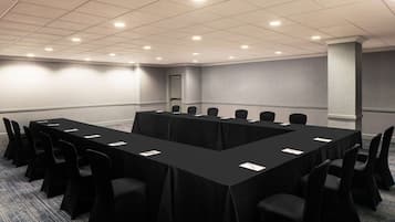 Una sala de conferencias con una larga mesa, sillas negras y piso alfombrado.