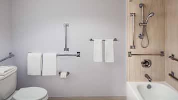 A bathroom with a toilet, two towel racks, a shower with a handheld showerhead, and a bathtub.