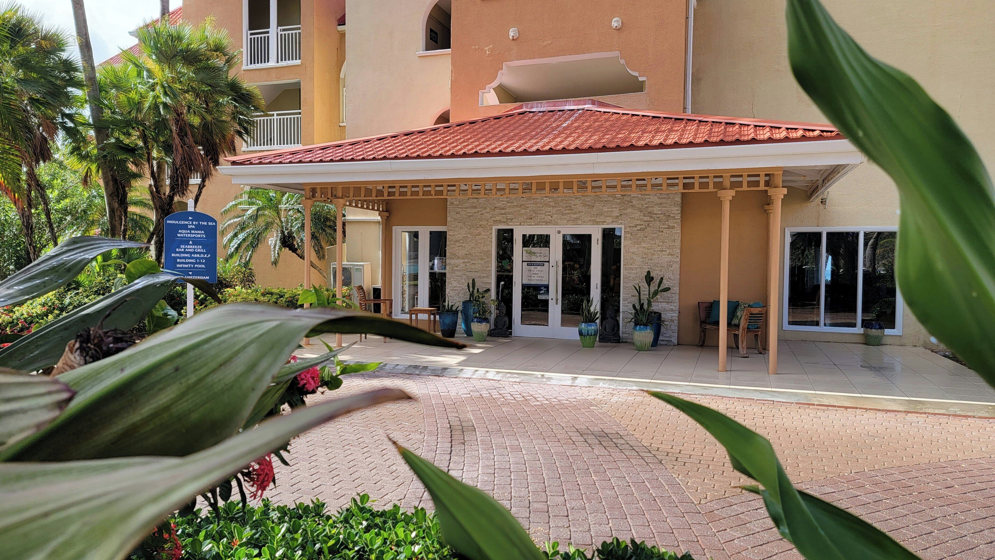 Entrada de hotel con tejado de tejas rojas, un patio cubierto y un cartel.