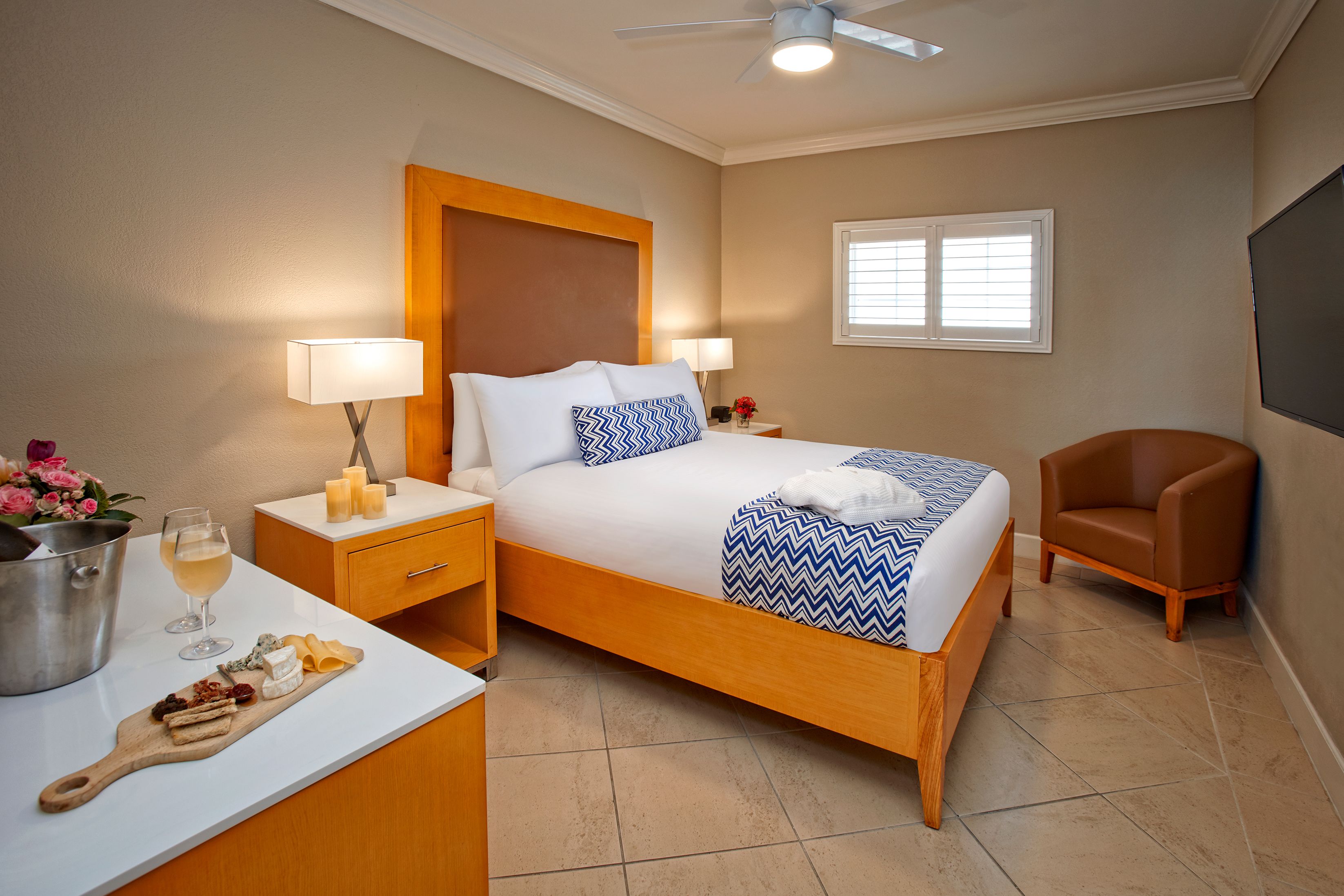 Une chambre d’hôtel comprenant un lit, des tables de chevet, une chaise, un bureau avec une lampe et une fenêtre.
