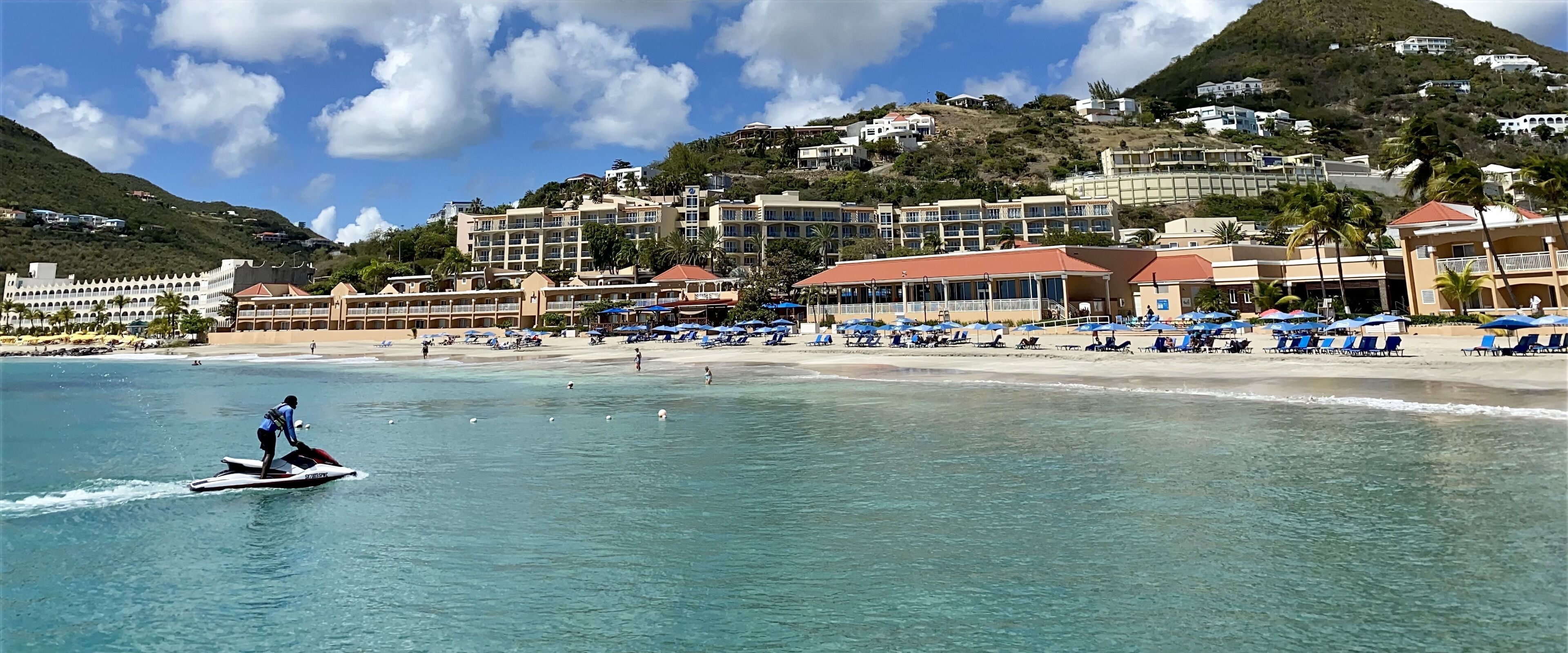 A coastal resort with beachfront villas, a sandy beach, and a clear blue sea.