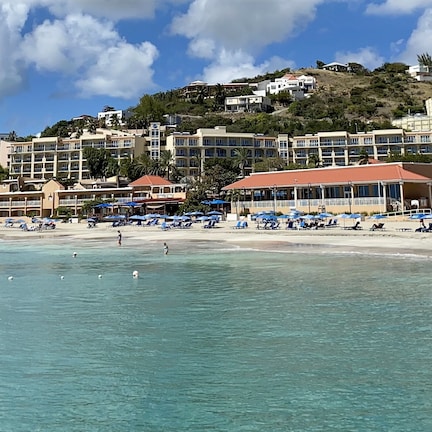 A coastal resort with beachfront villas, a sandy beach, and a clear blue sea.