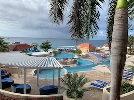 Zona de piscina en un resort con sillones de descanso, una piscina pequeña y vistas al océano.