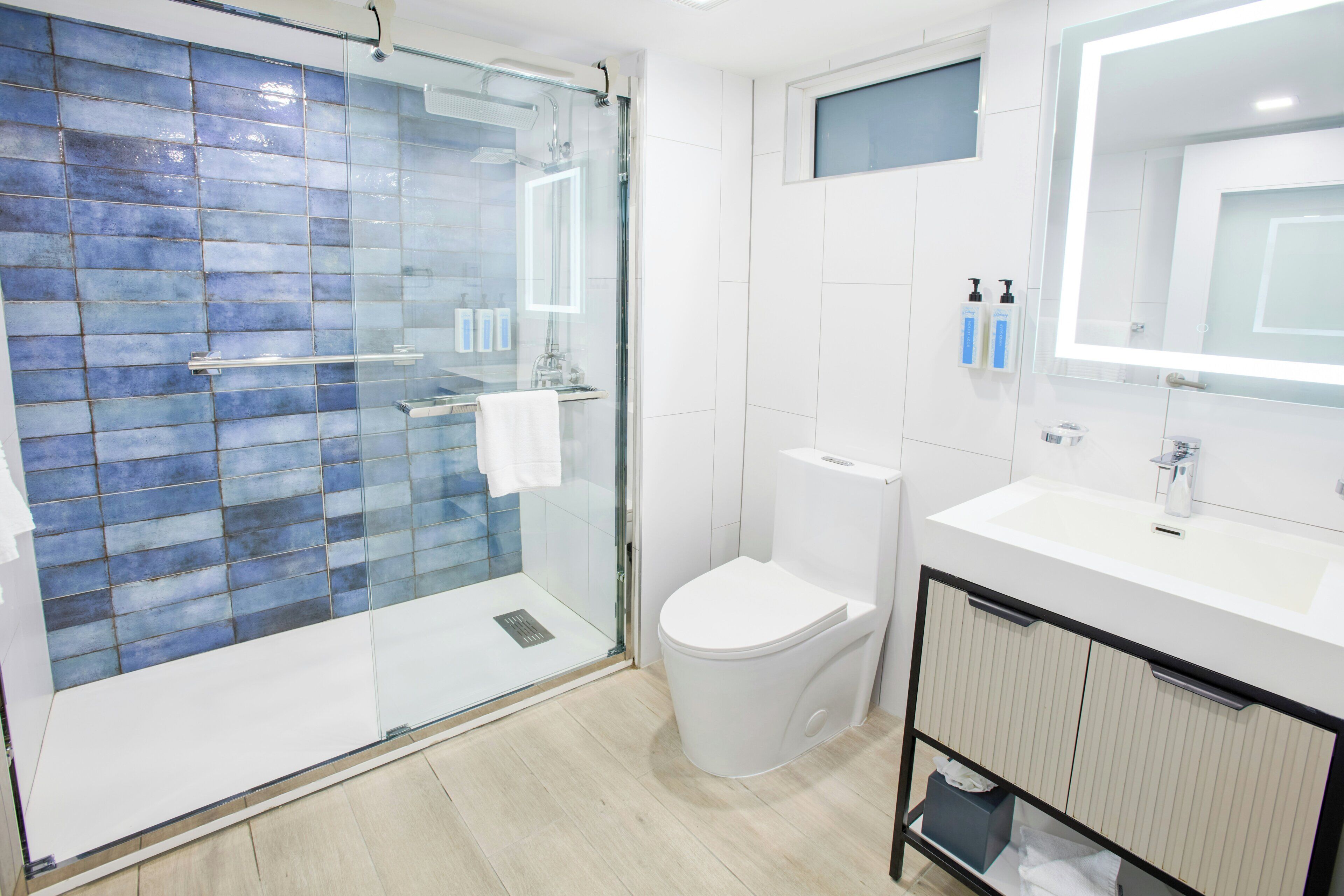 A modern bathroom with a glass-enclosed shower, a white toilet, and a vanity with a mirror.