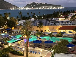 Un resort con varias piscinas, tumbonas y vistas al océano.