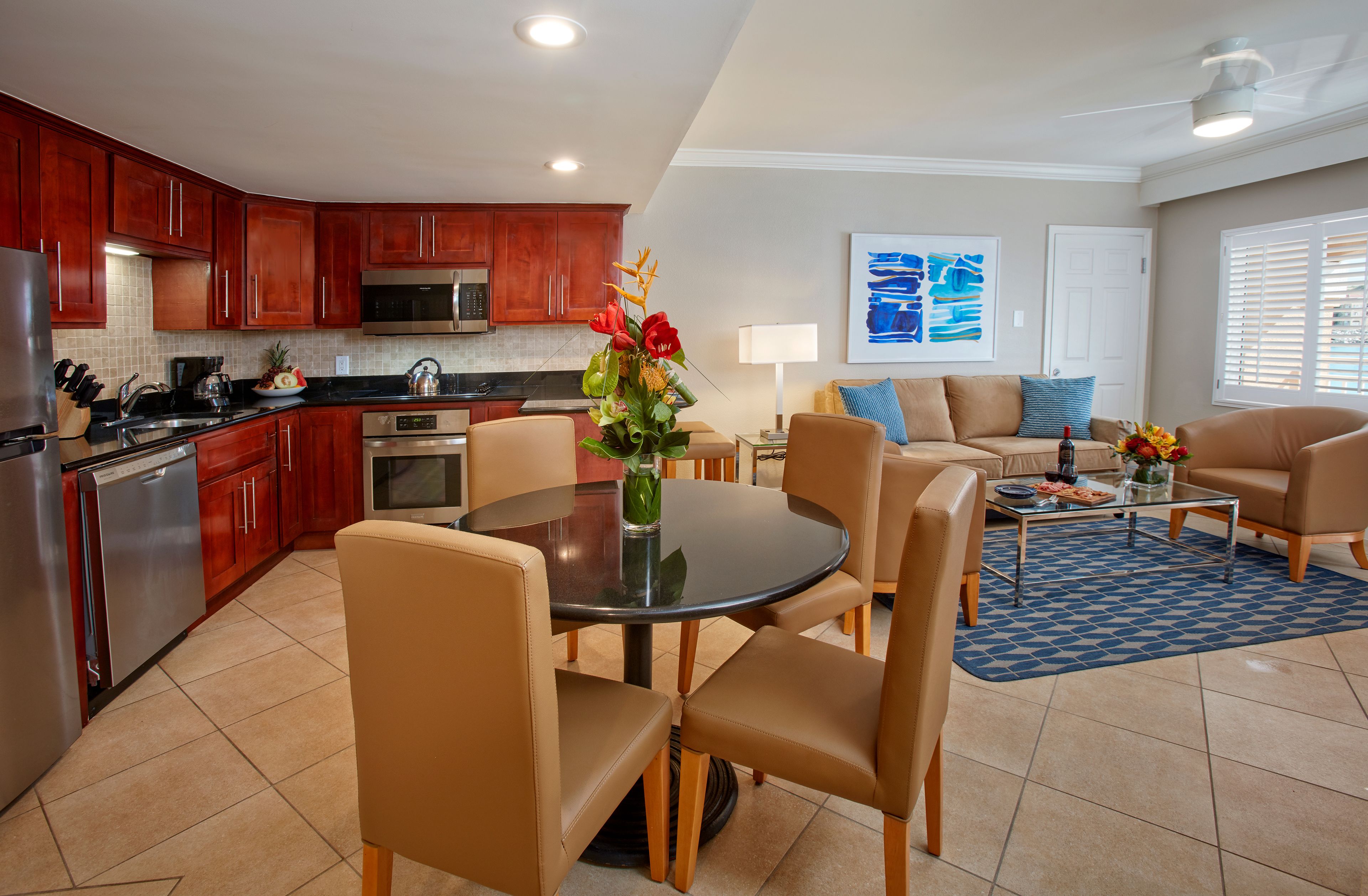 A modern kitchen with dark wood cabinets, stainless steel appliances, and a dining area with a round table and four chairs.