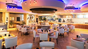 A hotel lobby with multiple seating areas, a central bar, and a kitchen visible in the background. - Divi Little Bay Beach Resort (Philipsburg)