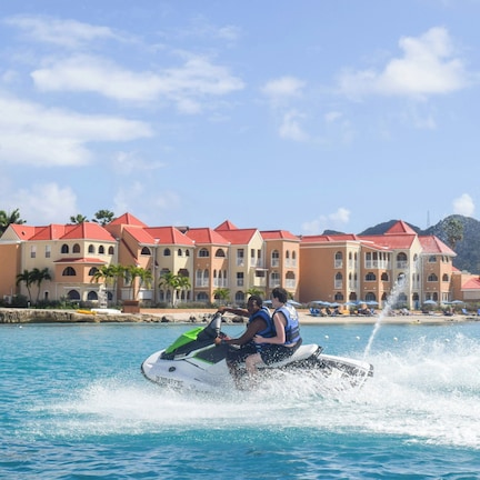 A water jet ski in motion with a resort and buildings in the background.