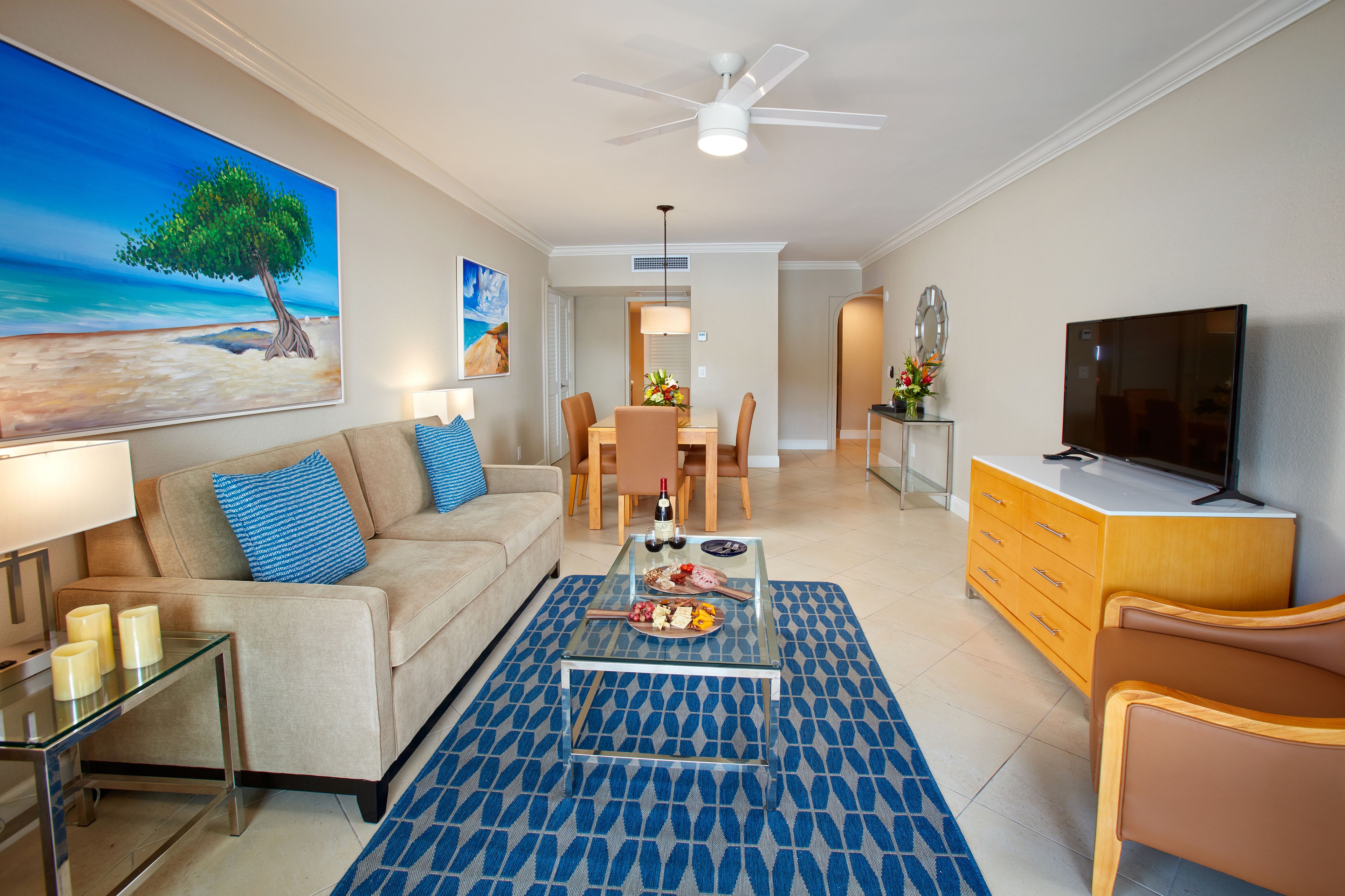 A modern living room with a sofa, coffee table, TV, and dining area.