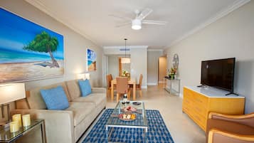A modern living room with a sofa, coffee table, TV, and dining area.