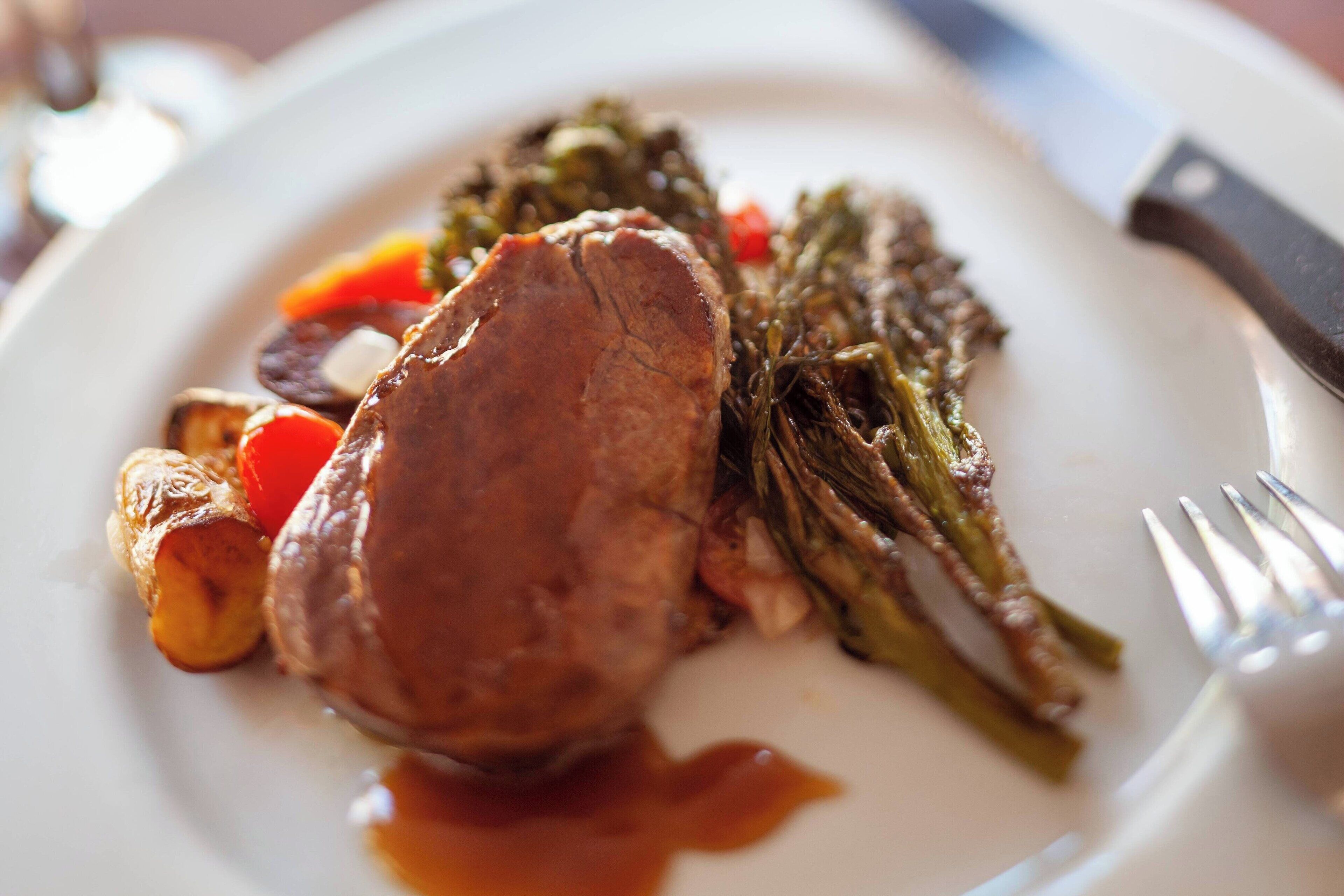 Un plato con carne, verduras y salsa.