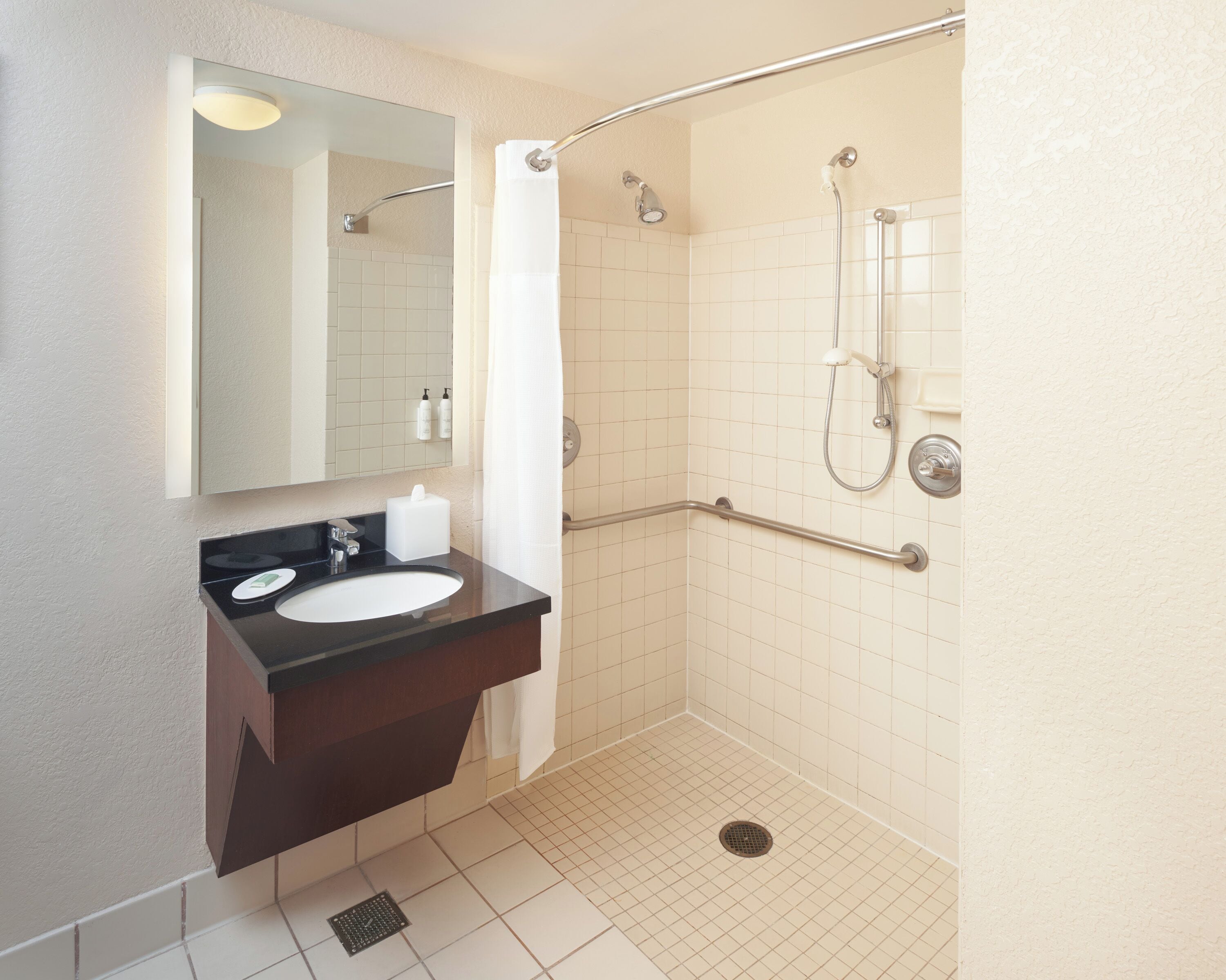 A bathroom with a shower, a sink, and a mirror.