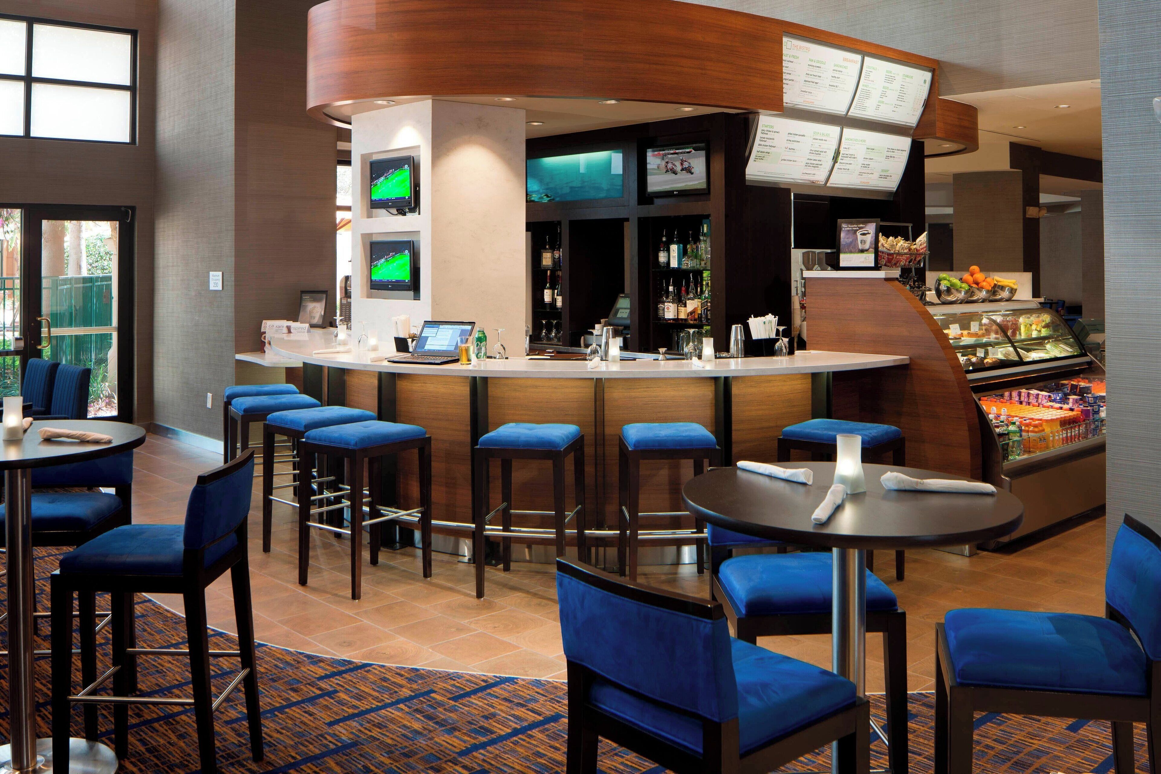 A hotel bar with multiple seating areas, a counter with a menu, and a display case with snacks.