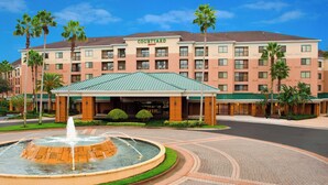 A Courtyard Marriott hotel with a central fountain, palm trees, and a brick-paved courtyard. - Courtyard Orlando Lake Buena Vista in the Marriott Village (Orlando)
