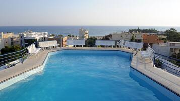 Alberca al aire libre, sombrillas en la alberca y camastros