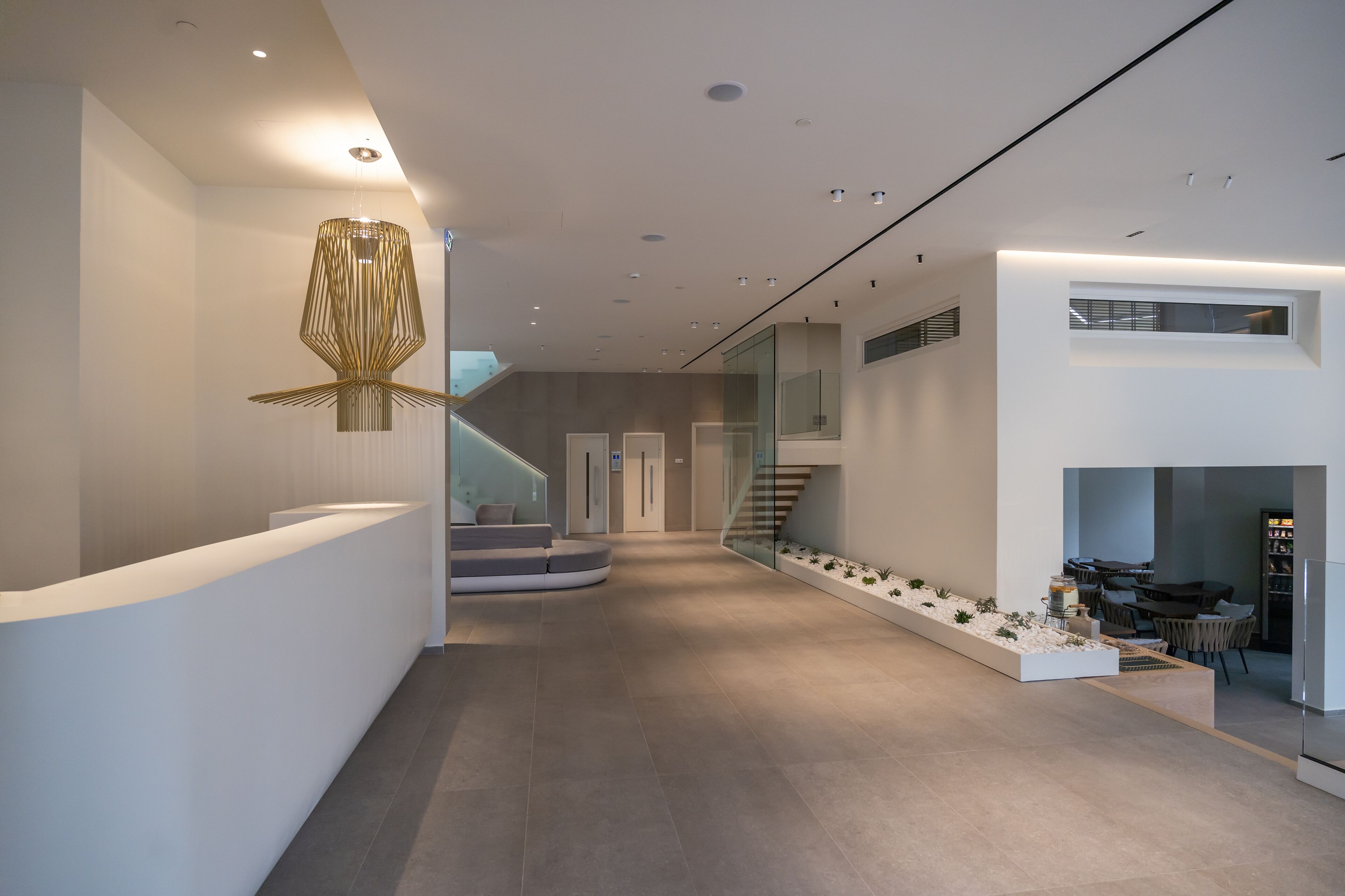 Un interior moderno con mostrador de recepción, una escalera y una zona de estar.