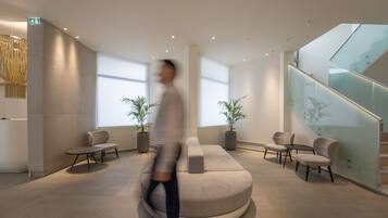 A modern lobby with a central seating area, glass railings, and potted plants.