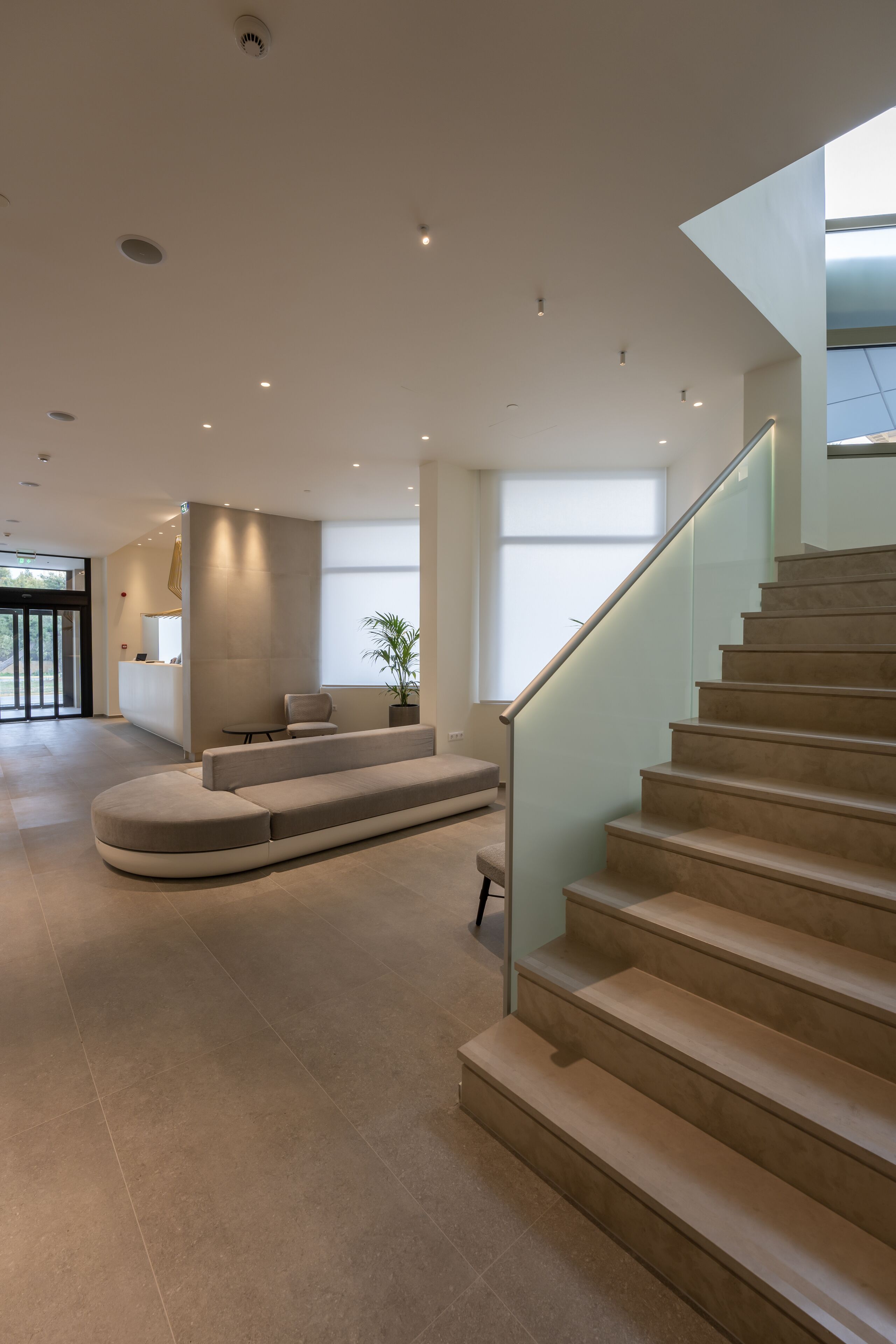 A modern interior with a curved seating area, a staircase, and a reception desk.