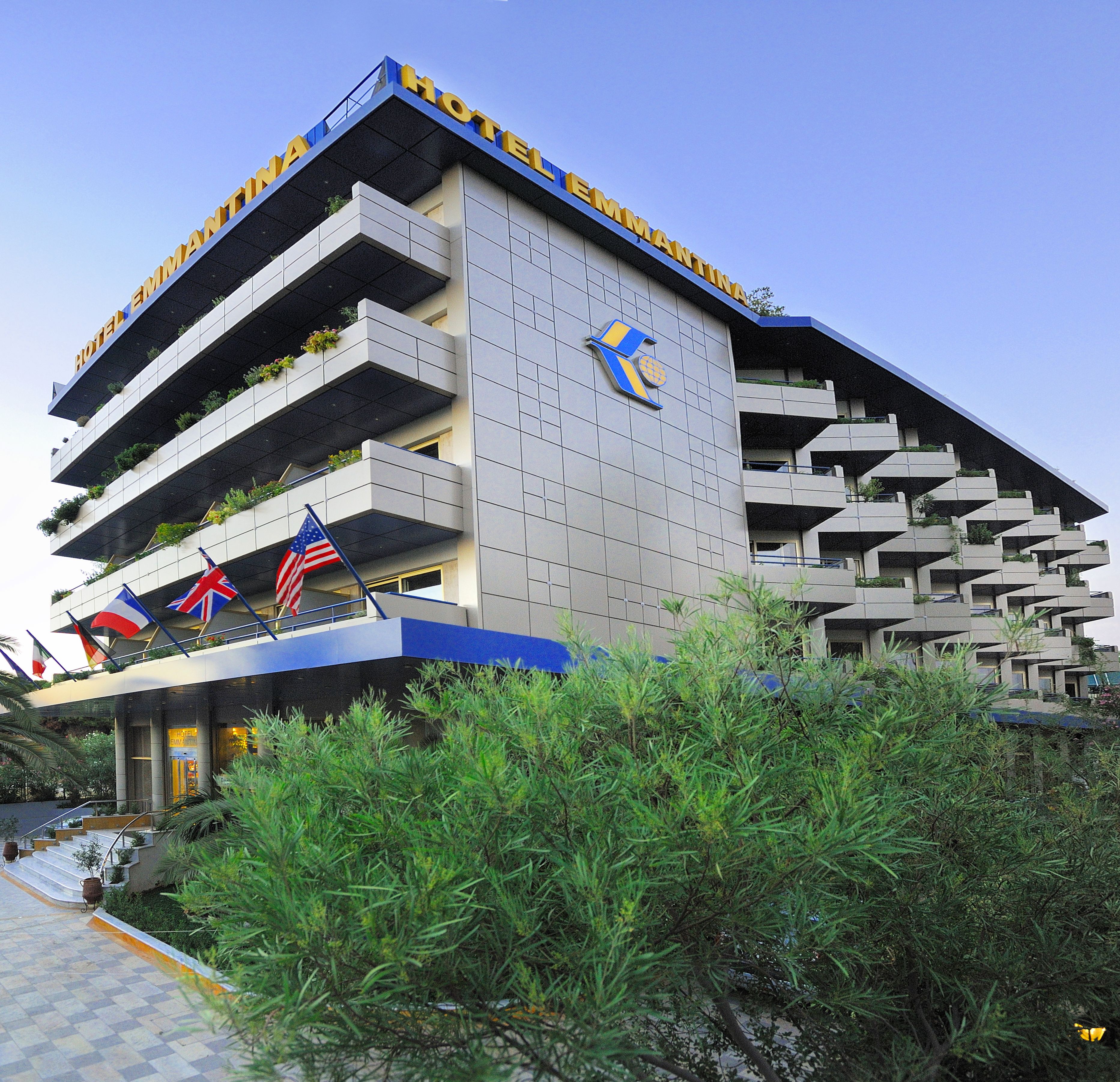 A modern hotel with a unique architectural design, featuring multiple balconies and a prominent logo on the facade.