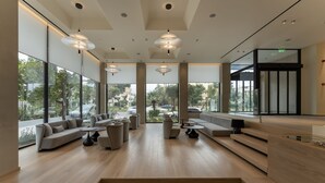 Un amplio vestíbulo con diseño moderno, que cuenta con un espacio de estar generoso con sofás y sillones, una escalera y grandes ventanales con vistas al exterior.