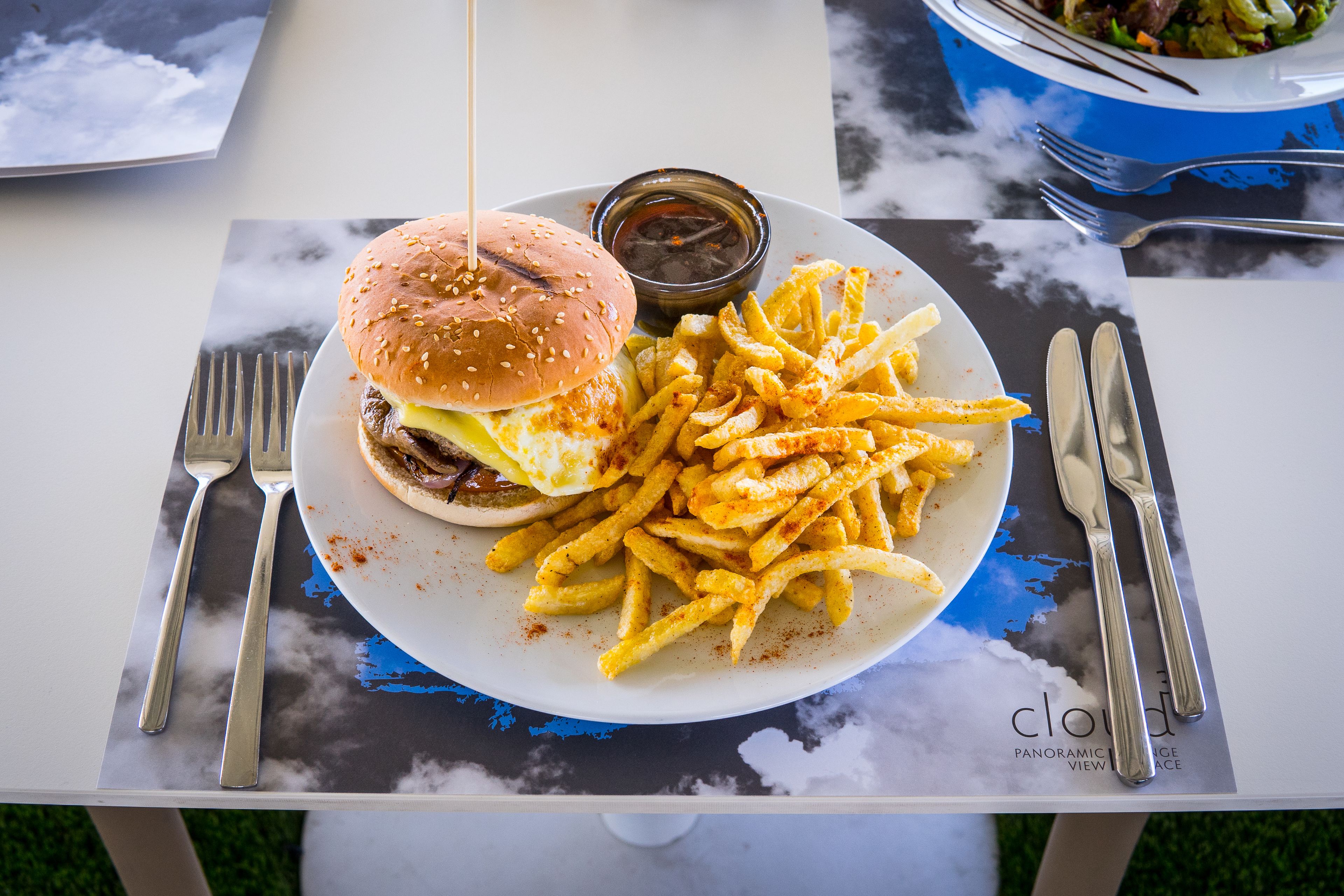 A plate with a hamburger and fries on a table with a placemat.