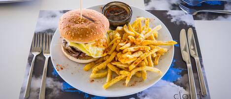 A plate with a hamburger and fries on a table with a placemat.