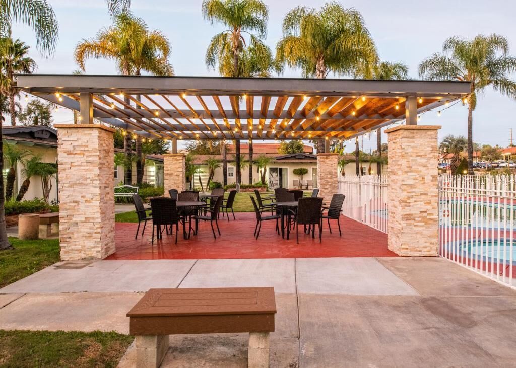 Eine Terrasse im Freien mit einer Pergola, Steinsäulen und Gartenmöbeln.