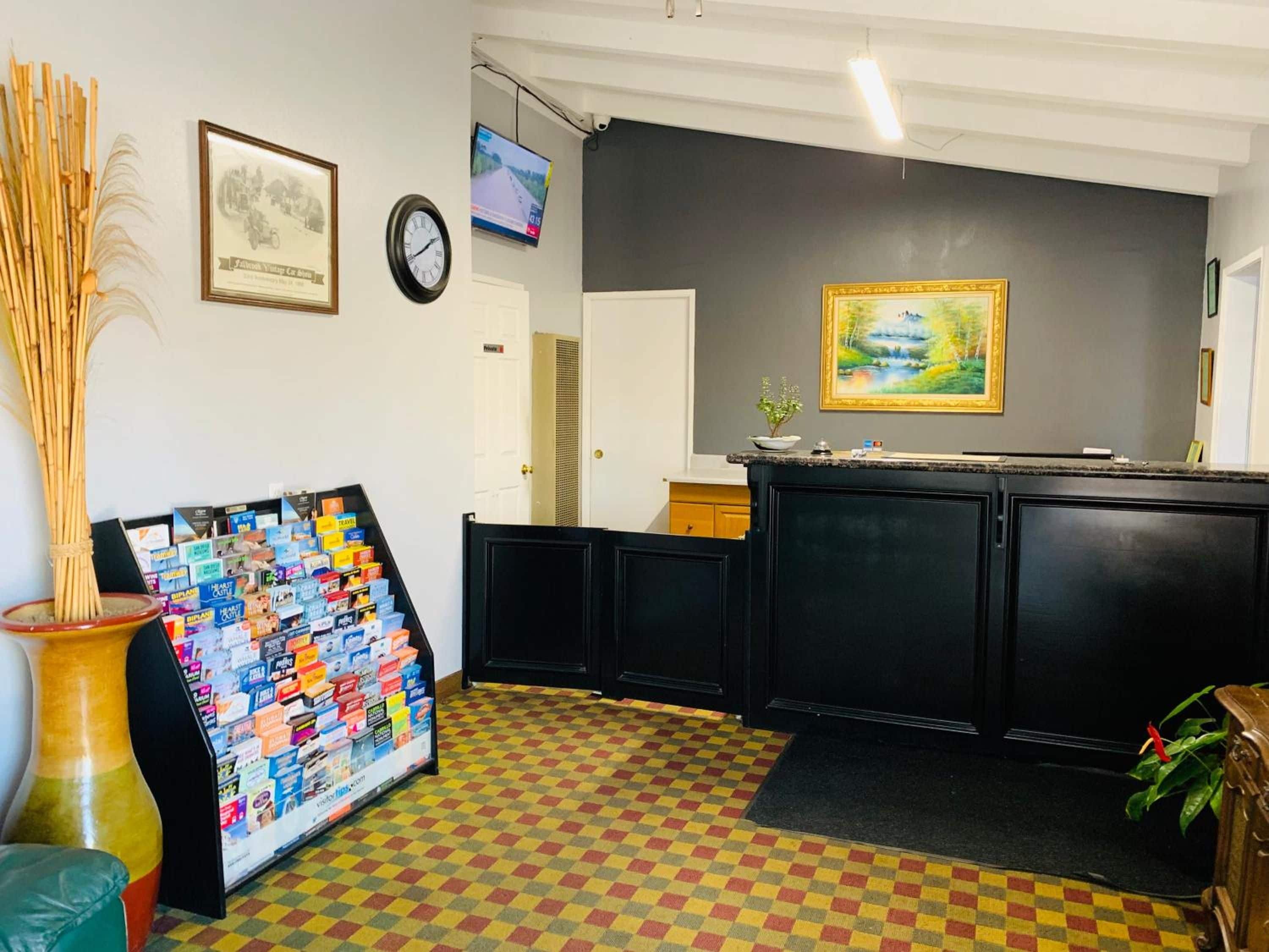 A reception area with a check-in counter, a wall clock, a television, and a framed picture.