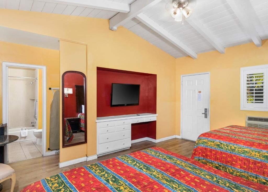 A bedroom with a bed, a television, a wardrobe, and a bathroom.