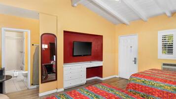 A bedroom with a bed, a television, a wardrobe, and a bathroom.