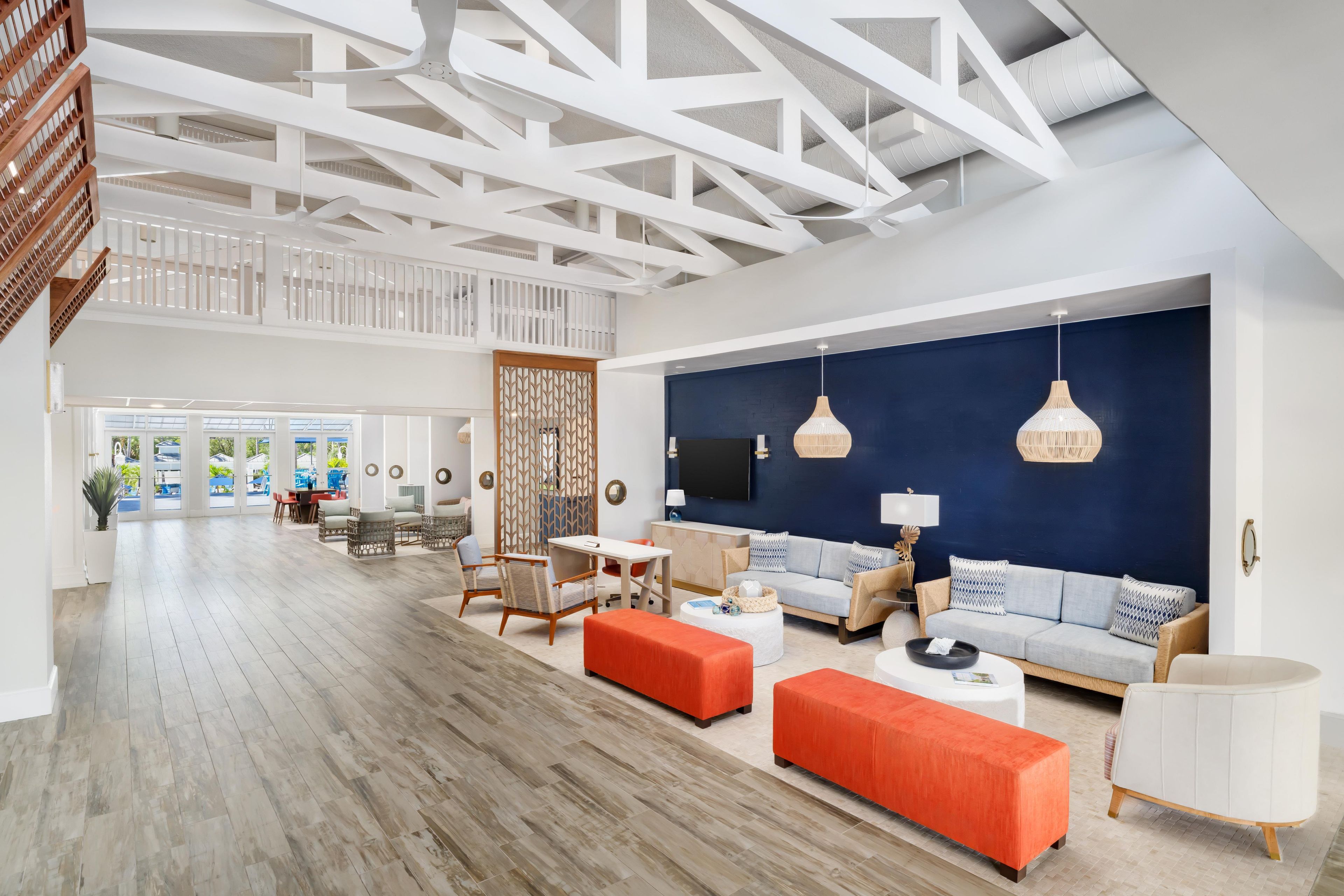 A spacious living area with a high ceiling, a blue accent wall, and modern furniture.