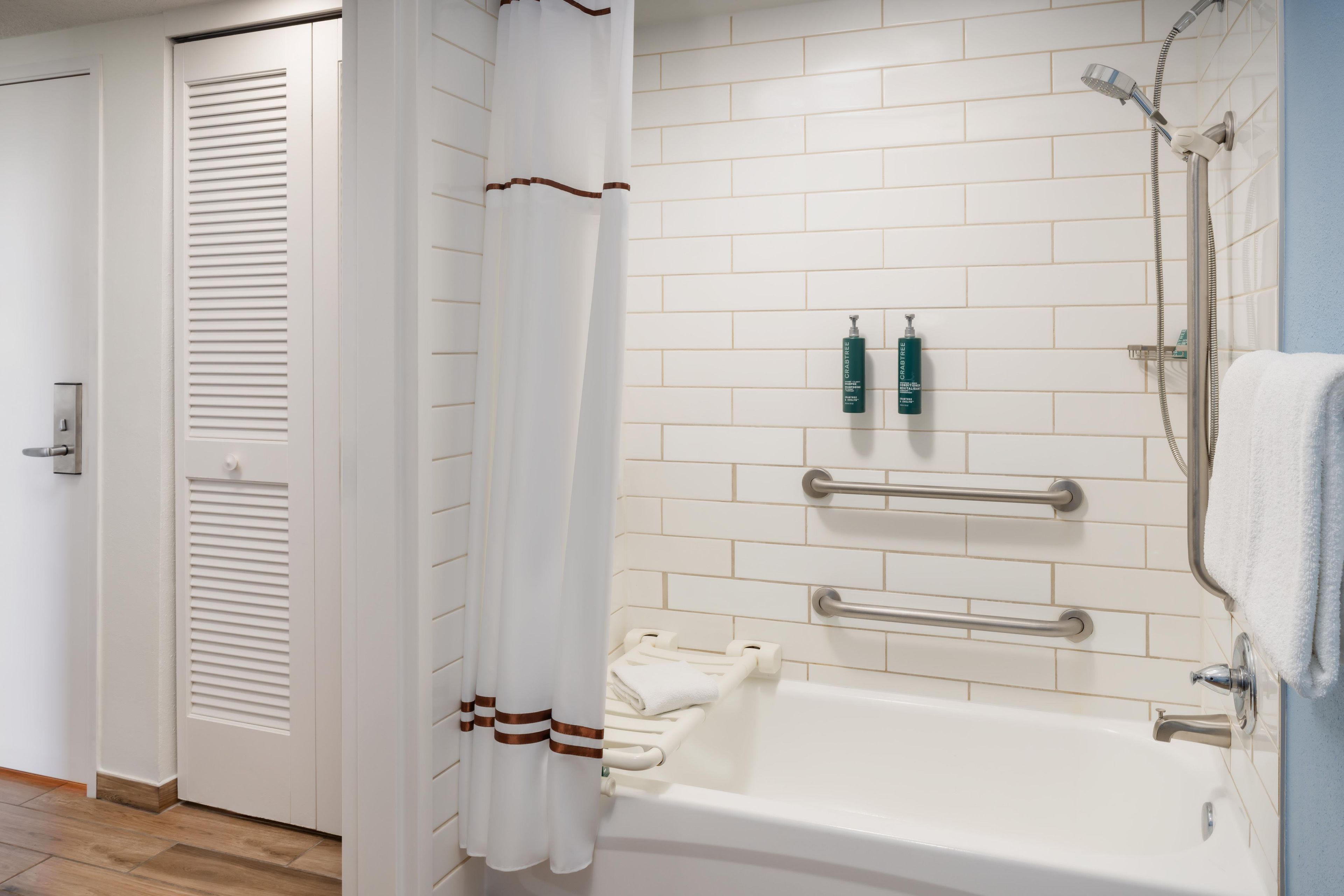 Un baño con una bañera blanca, ducha, toallero y dispensador de papel higiénico.