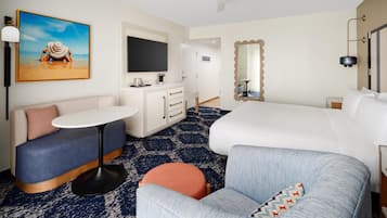 Habitación de hotel con cama, sofá, una mesita, televisor, espejo y ventilador de techo.