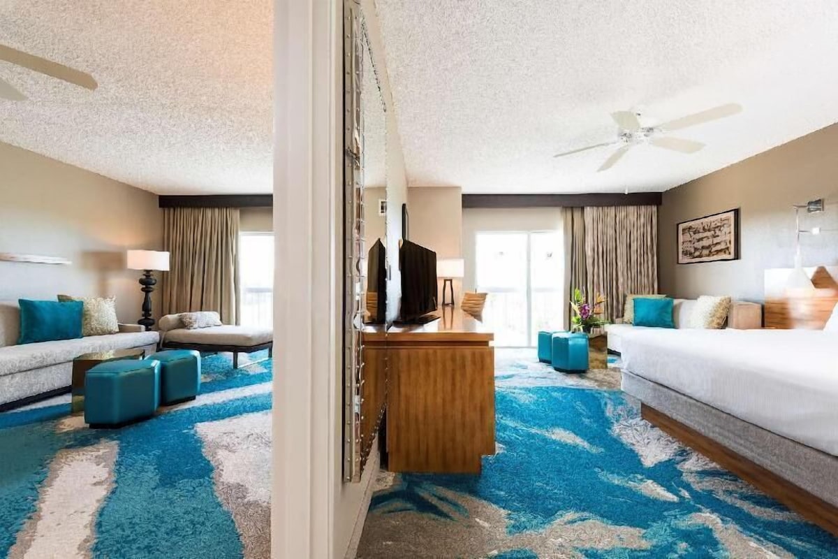 Ein Hotelzimmer mit Bett, Schreibtisch, einer Couch und einem großen Fenster.