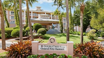 A sign for the Doubletree by Hilton Grand Key Resort with a view of the resort's building and surrounding tropical landscaping.