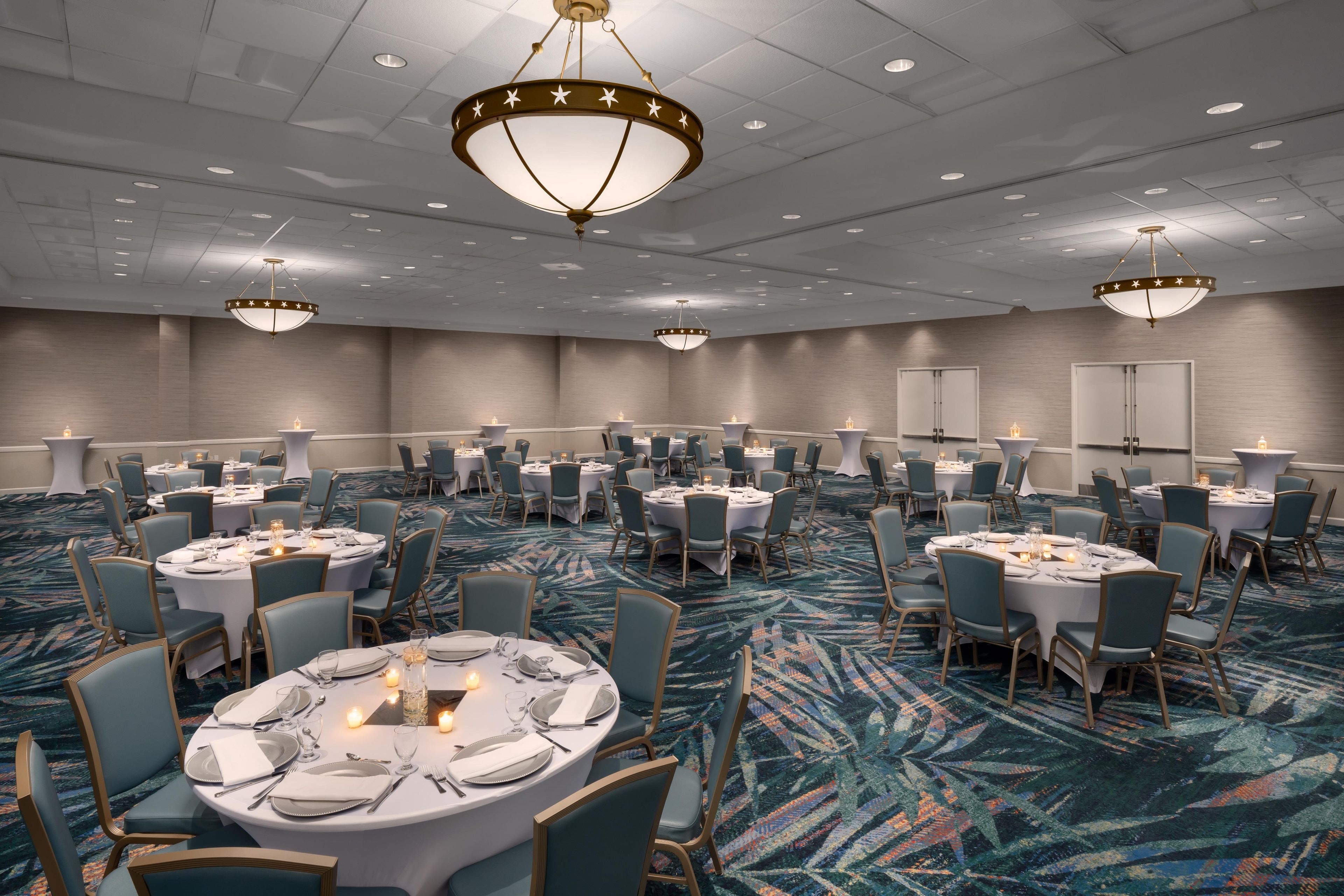 A conference room with round tables, chairs, and chandeliers.