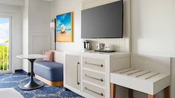 Une pièce moderne avec un meuble blanc, une table ronde, un canapé et un grand téléviseur fixé au mur.