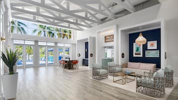 A spacious room with a high ceiling, large windows, and a view of palm trees.