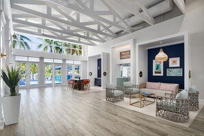 A spacious room with a high ceiling, large windows, and a view of palm trees.