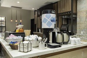 A buffet setup with various food items, a coffee station, and a beverage dispenser. - Hilton Garden Inn Phoenix Airport (Phoenix)