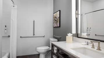 Un baño moderno con inodoro, bidé y tocador con lavamanos y espejo.