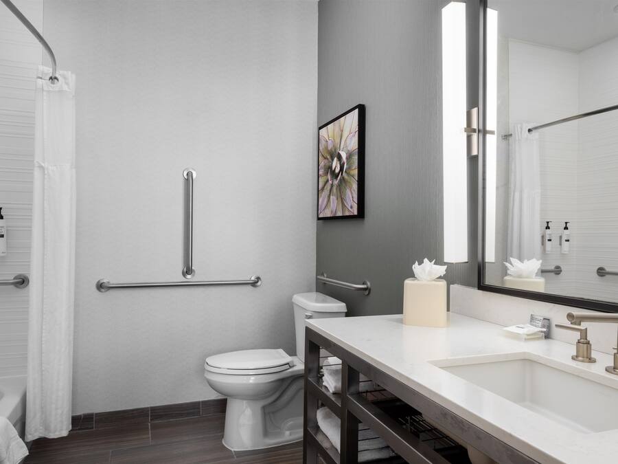 Un baño moderno con inodoro, bidé y tocador con lavamanos y espejo.