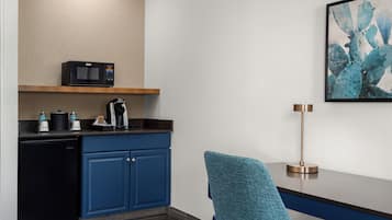 Cocina americana compacta con microondas, cafetera y refrigerador.