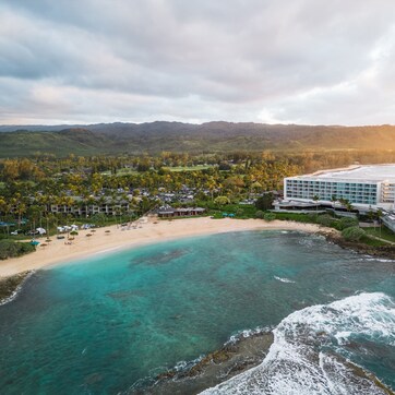 A resort with a beach, ocean, and mountainous backdrop.
